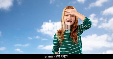 red haired girl holding to her head over sky Stock Photo