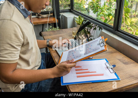 Freelancer working with laptop on wooden table next to window Stock Photo