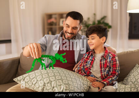 father and son playing with toy dinosaur at home Stock Photo