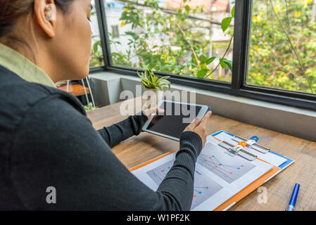 Woman using digital tablet at workplace next to window Stock Photo