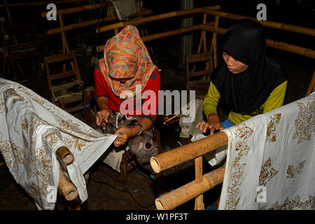 yogyakarta, indonesia - 2015.11.10: young women applying wax patterns on textile fabrics in a batik factory Stock Photo