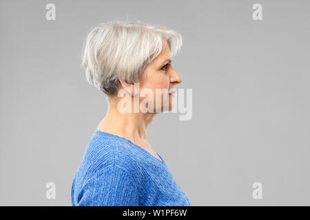portrait of senior woman in blue sweater over grey Stock Photo