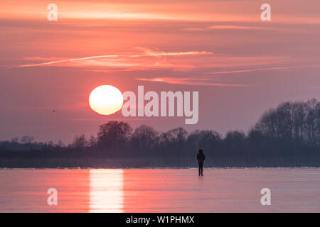 Red sunset in winter over a frozen lake in Germany Stock Photo
