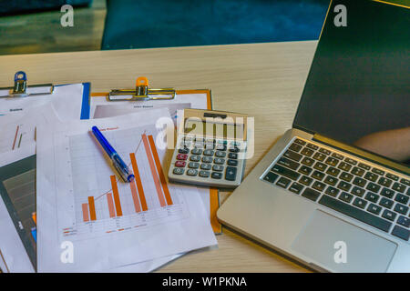 Close up of laptop graph documents on office desk Stock Photo