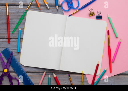 Blank notepad and childrens art supplies on a wooden background Stock Photo