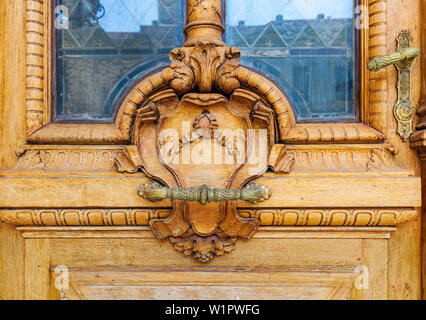 Closeup of wooden floral pattern engravings and handlebar on old door leaf Stock Photo