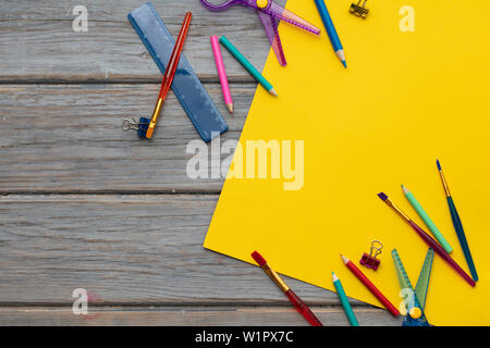 Childrens art and craft composition. Art supplies and yellow paper on a desk Stock Photo