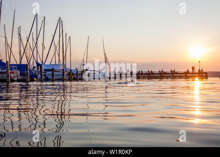 People on a jetty at the Sunset at the Ammersee lake, Bavaria, Germany, Europe Stock Photo