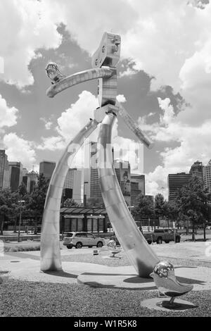 The Traveling Man-Walking Tall Art Sculpture by Brad Oldham in front of the Dallas Texas Skyline. Stock Photo