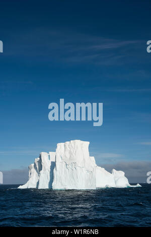 A massive iceberg floats on the open sea above a blue sky, near South Shetland Islands, Antarctica Stock Photo