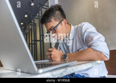Hard-working young man using laptop cellphone and concentrating Stock Photo