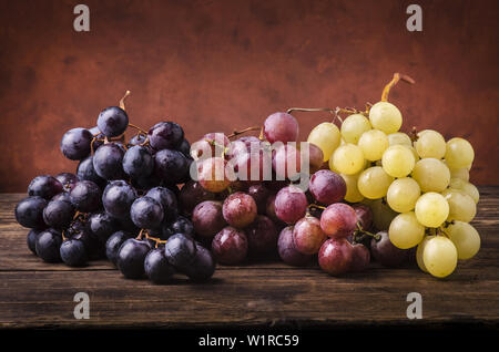 bunches of grapes of different types on a rough wooden table Stock Photo