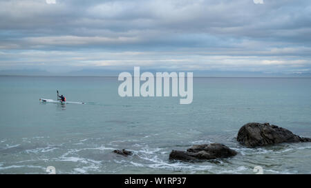 A canoeist paddles along the False Bay coastline during the winter months near Cape Town in South Africa Stock Photo