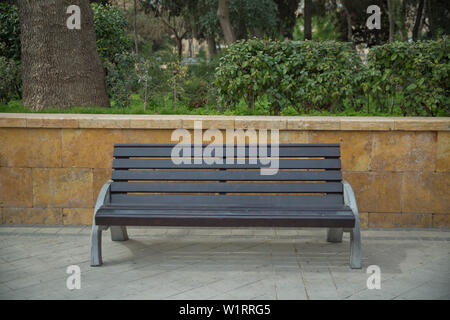 Wooden bench in the city park. Empty wooden bench in the background of trees Stock Photo