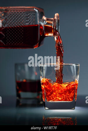 Pouring whiskey or scotch  into glass. Alcoholic drink pouring from a decanter into a glass. Stock Photo