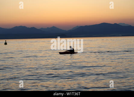 Lonely paddler on the lake during the sunset Stock Photo