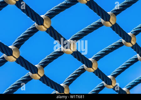 Rope mesh against a bright blue sky closeup, climbing park, playground for play and sport Stock Photo