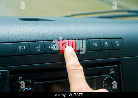 Car emergency button switch, finger press on button switch for turn on flasher light during hazard or danger situation Stock Photo