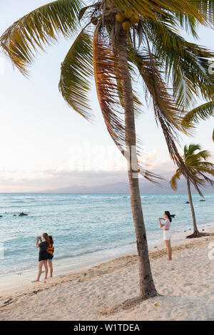 female tourists, women, taking pictures on the beach at sunset, palm tree, lonely coast road from La Boca to Playa Ancon, with beautiful small sandy b Stock Photo