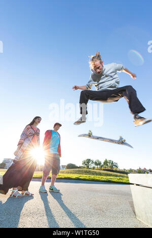 Skater jumping with his skateboard from bench, kickflip, ollie, sunset, hipster, swimming meadow, provincial capital, Mecklenburg lakes, Schwerin, Mec Stock Photo