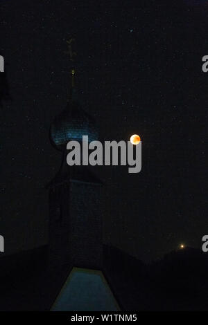 Blood Red Moon in the lunar eclipse 2018; in the front of the bell tower of the church of almau for overseas Stock Photo
