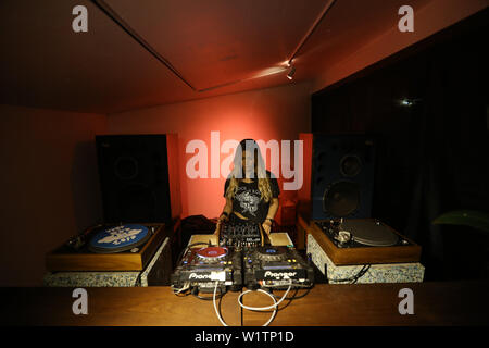 Blonde woman DJ playing and mixing vinyls in dark music club in the night. Stock Photo