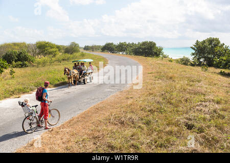 woman with child cycling along the lonely coast road from La Boca to Playa Ancon, with beautiful small beaches in between, turquoise blue sea, family Stock Photo