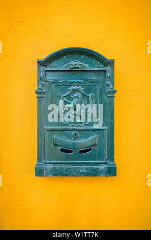 Green, old, vintage mailbox hanging on the yellow wall Stock Photo
