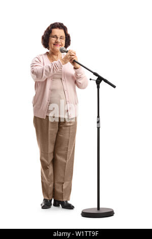 Full length portrait of an elderly woman standing in front of a microphone on a stand isolated on white background Stock Photo