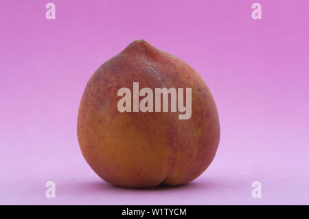 A ripe peach of reddish color and smooth skin, isolated on violet background Stock Photo