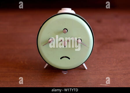 An old Junghans mechanical alarm clock on a wooden table. Stock Photo