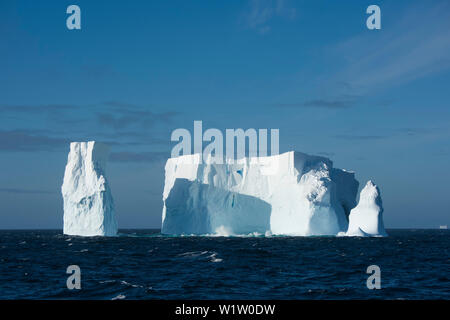 An iceberg, once much larger, but now featuring three towers, floats in the open sea, near South Shetland Islands, Antarctica Stock Photo