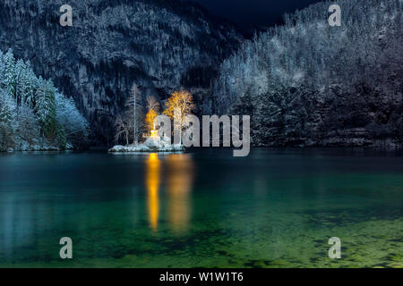 The small island in the Lake Königssee with illuminated John Christian Lieger statue in winter mountain scenery Stock Photo