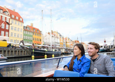Copenhagen tourists people on cruise boat tour on water canal in old port Nyhavn. Young multiracial couple visiting famous European destination in Europe during fall or spring. Stock Photo