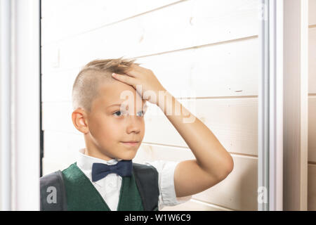 A 10-year-old boy prepares for school after a long summer break. Back to school. In front of the mirror Stock Photo