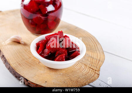 Pickled red betroot in bowl and jar on wooden background. Stock Photo