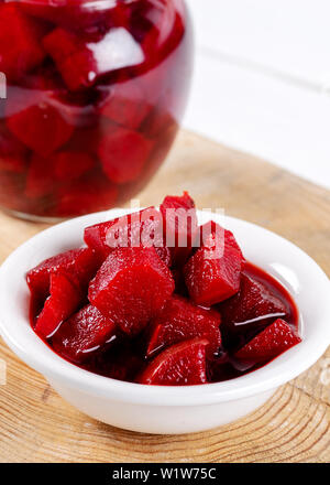 Pickled red betroot in bowl and jar on wooden background. Stock Photo