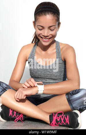 Active runner woman using activity tracker smartwatch as heart rate monitor for workout tracking her weight loss improvement. Woman working out at gym living a healthy life. Wearable tech. Stock Photo