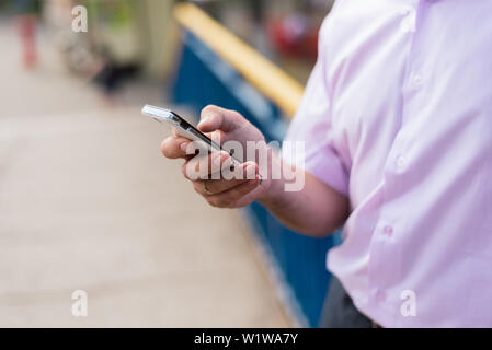 phone in the hands of a man on the street. dependence on mobile, social networks. The problem of modernity Stock Photo