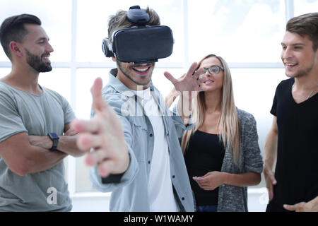 Young handsome man wearing virtual reality goggles touching controls to shoot in game Stock Photo