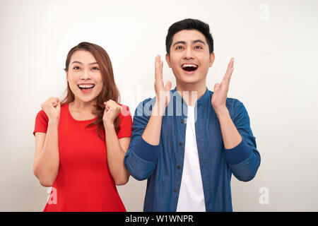 Young asian couple in love over isolated background celebrating surprised and amazed for success with arms raised and open eyes Stock Photo