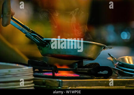Stainless steel pan on the stove with a yellow flame. Stock Photo