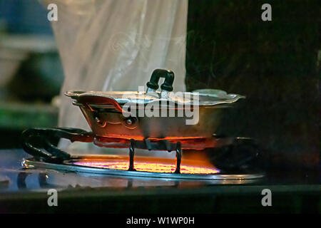 Stainless steel pan on the stove with a yellow flame. Stock Photo