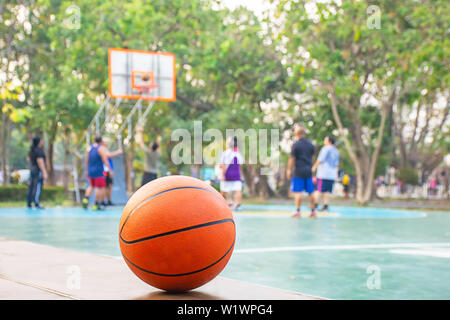 Basketball on the wooden chair Background Blurry image of people playing basketball on a court. Stock Photo