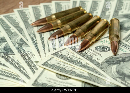 6 rifle cartridges on hundred dollar bills. Concept for crime, contract killing, paid assassin, terrorism, war, global arms trade, weapons sale Stock Photo