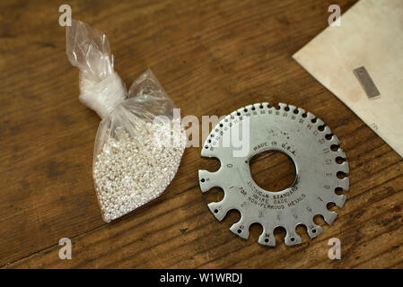 Sterling silver pieces (for melting) and sheet/wire gauge (to measure the material just insert it through the slots). Silver workshop in Taxco, Mexico Stock Photo