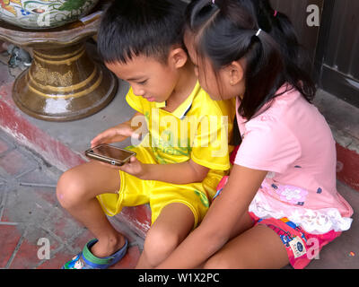 Two small pre-school children in Bangkok, Thailand, watching a cartoon on a mobile phone Stock Photo