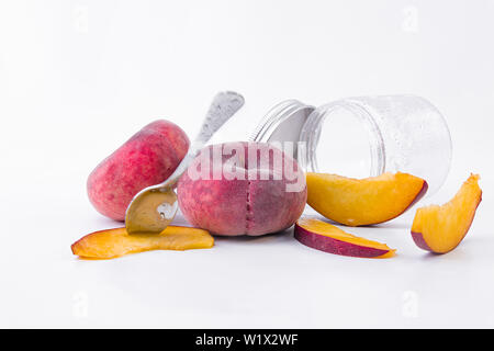 Red and ripe flat peaches - Fresh slices of sweet flat peach with a glass glass on a white background - Close-up Stock Photo