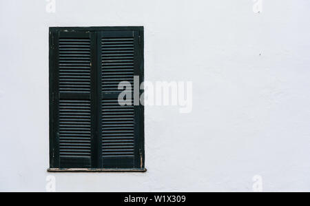 Window and green wooden louvres on white wall with space for copy. Stock Photo