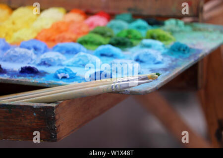 Brushes and palette with multi-colored paints. Concept of the artist studio, painting and creativity Stock Photo
